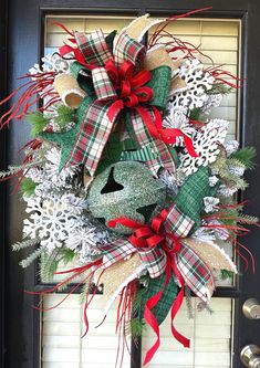 a christmas wreath with bells and snowflakes hanging from the front door, decorated with red ribbon