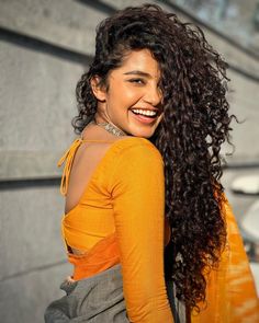 a woman with long curly hair smiling at the camera