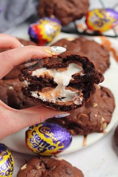 a hand holding an oreo cookie with white frosting and chocolate eggs in the background