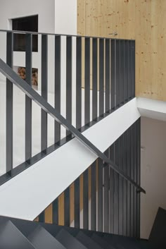 a staircase with black and white railings next to a wooden wall