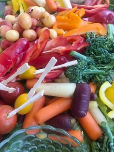 many different types of vegetables are in a glass bowl with toothpicks on them