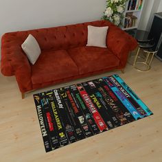 a red couch sitting on top of a hard wood floor next to a black rug