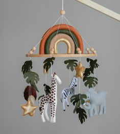 a mobile with animals and plants hanging from it's sides in front of a gray wall