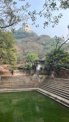 an outdoor pool with steps leading up to the top of a hill in front of a building