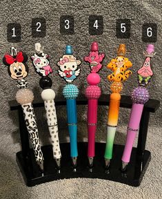 several different pens are lined up on a black holder with numbers in the bottom row