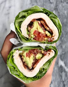 two wraps filled with meat and lettuce on top of each other in someone's hand