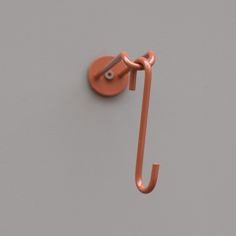 an orange umbrella hook is hanging on a gray wall and there are two hooks attached to it