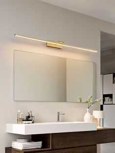 a bathroom with a sink, mirror and lights on the wall above it's counter