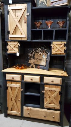 a wooden cabinet with doors and drawers on it's sides, in front of a black wall