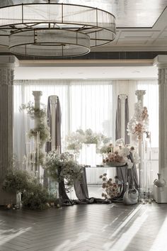 the room is decorated with flowers and vases on the table in front of large windows