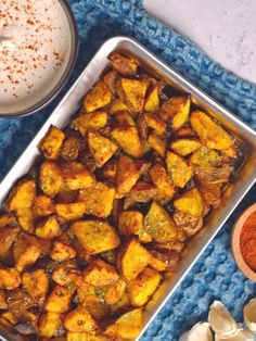 a pan filled with cooked potatoes next to a glass of milk on a blue towel