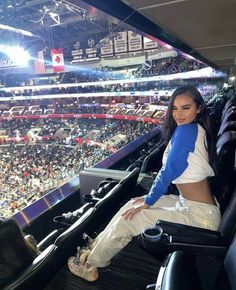 a woman sitting in the bleachers at a baseball game wearing white and blue