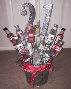 a bucket filled with lots of liquor bottles and silver numbers sitting on top of a carpeted floor