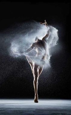 a ballerina is dancing in the dark with powder all over her body and arms