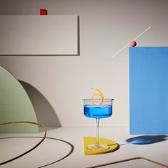 a blue drink sitting on top of a table next to a yellow coaster and an object