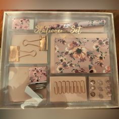 the contents of a stationary set in a clear box with flowers and gold hardware on it