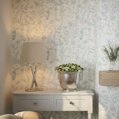 a small table with a flower pot on top of it next to a lamp and chair