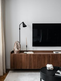 a large flat screen tv mounted to the side of a wooden cabinet in a living room