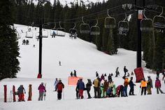 a group of people standing on top of a snow covered slope under a ski lift