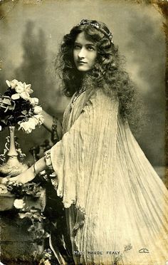 an old fashion photo of a woman with long hair holding a flower in her hand