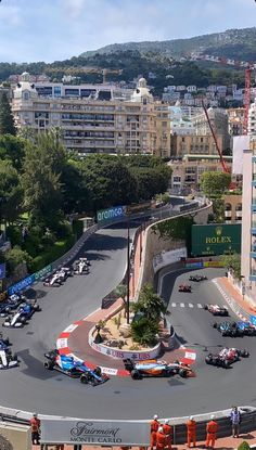 an aerial view of a race track with cars driving on it and buildings in the background