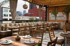 an outdoor restaurant with tables and chairs set up for dinner on the roof terrace overlooking cityscape