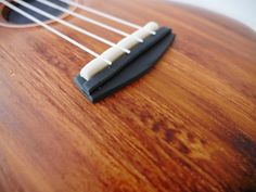 a close up of the strings on an acoustic guitar with wood grain and white strings