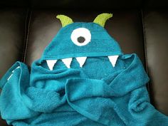 a blue towel with a monster face on it sitting in a chair next to a stuffed animal