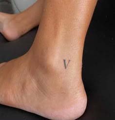 a person with a small v tattoo on their left foot and the word v written in black ink