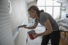 a woman is painting the wall in her living room