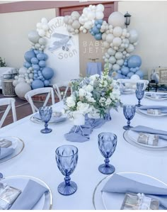 a table set up for a baby shower with blue and white decorations on the wall