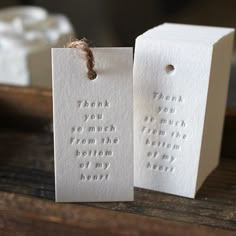 two white tags with words on them are sitting on a table next to a box