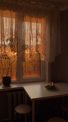 a window with sheer curtains in front of a table