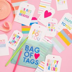 many different tags on a pink surface with some scissors and other items around the tag