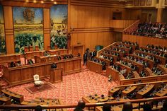 a large room filled with lots of people sitting at desks in front of wooden paneled walls