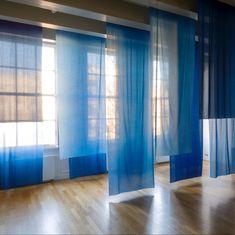 an empty room with blue curtains and wooden floors