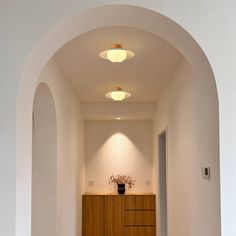 an archway leading into a room with a vase on the door and lights above it