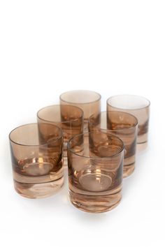 six brown glasses sitting next to each other on a white surface