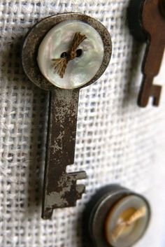 an old key with a hole in the middle is hanging on a white fabric wall