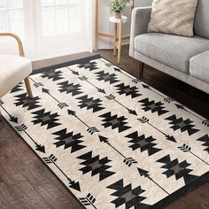 a black and white rug with arrows on it in front of a gray couch next to a chair