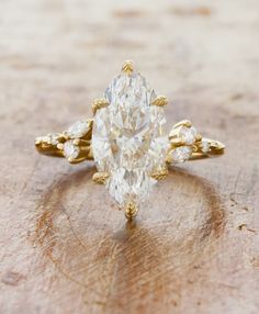 a pear shaped diamond ring sitting on top of a wooden table