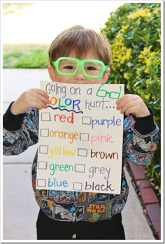 a young boy wearing glasses holding up a sign with words written in different colors on it