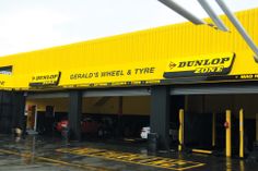 a yellow building with cars parked in front of it on a wet parking lot next to the road