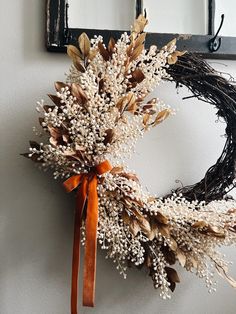 a wreath is hanging on the wall next to a mirror with an orange ribbon tied around it