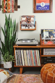 a record player sitting on top of a wooden table next to a potted plant