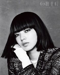 black and white photo of a woman with bangs wearing a sweater looking at the camera