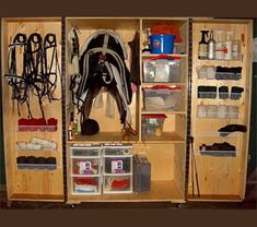 the inside of a wooden storage cabinet with lots of items on shelves and bins