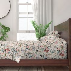 a bed sitting next to a window with a plant in the corner on top of it