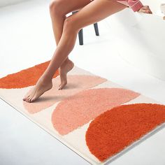 a woman sitting on top of a chair in front of a rug with an orange and white design