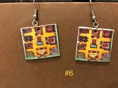 pair of earrings with yellow and black squares on them sitting on top of a cardboard box